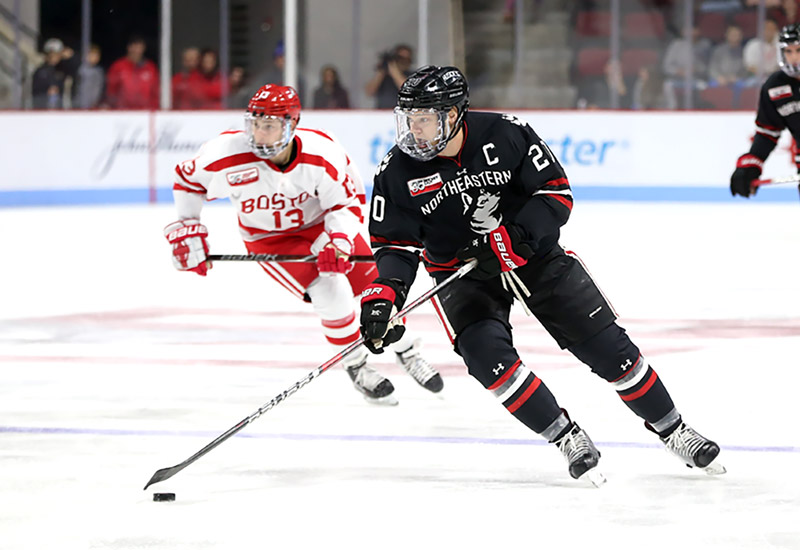 Northeastern hockey player on ice rink during a match.