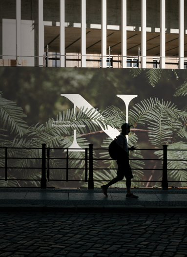 Student walking and mural with Northeastern logo in background.