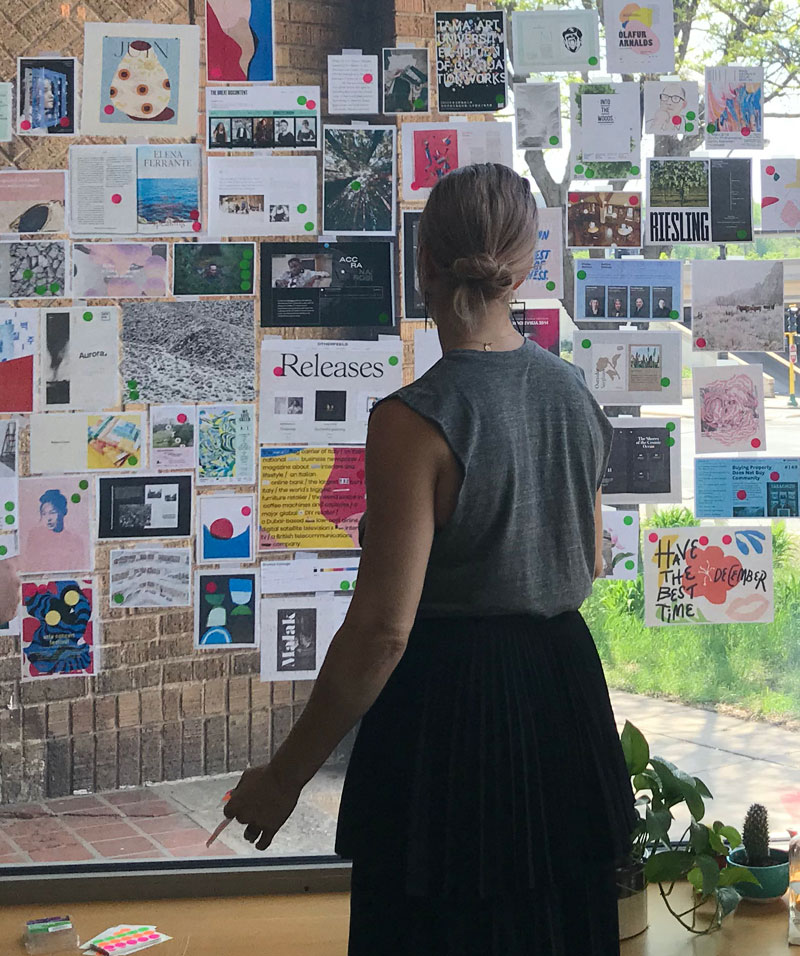 Person standing in front of window with lots of papers attached to it.